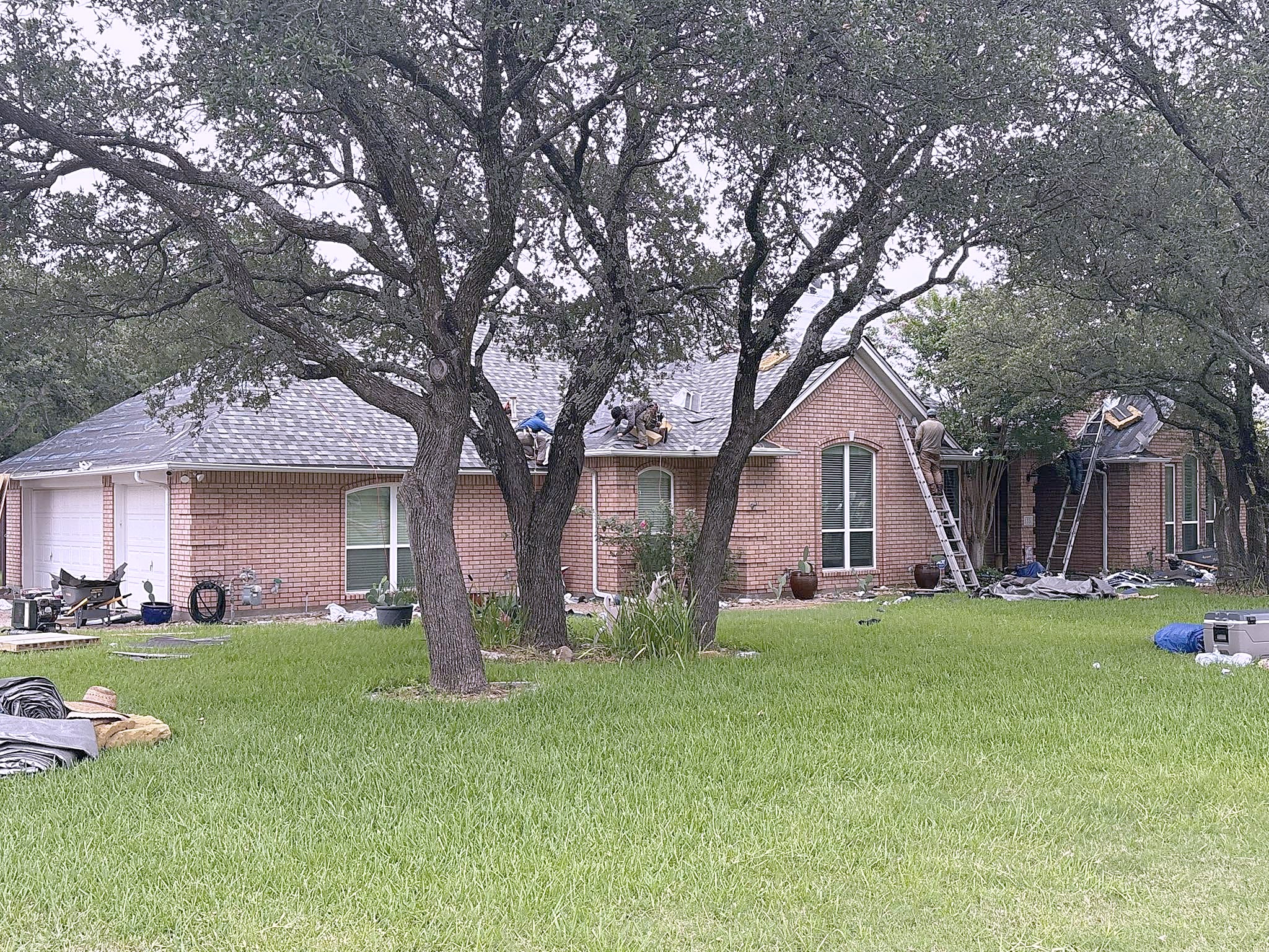 A crew on the roof of a brick ranch in Aledo during a re-roof, with tear-off debris below