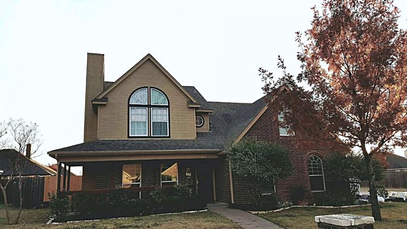 A two-story brick home with a steep front gable and a finished shingle roof