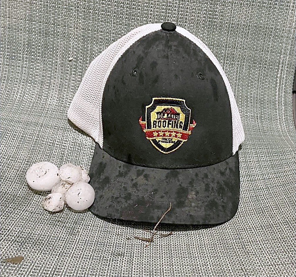 Hailstones beside a Top Rated Roofing cap splattered with hail